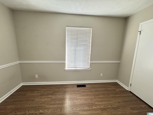 spare room with visible vents, dark wood finished floors, a textured ceiling, and baseboards