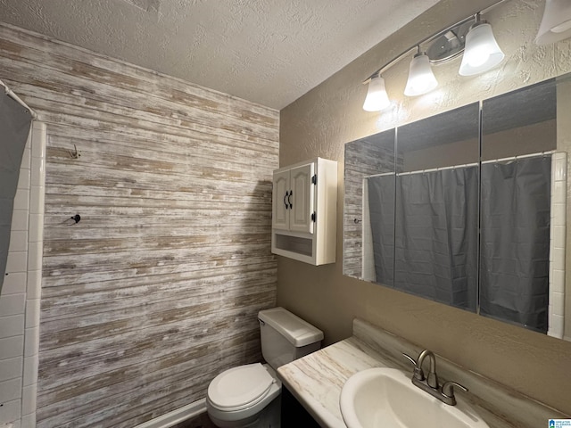 bathroom featuring a textured ceiling, a textured wall, toilet, a shower with shower curtain, and vanity