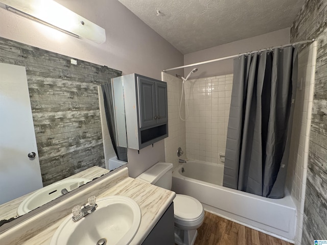 full bathroom featuring toilet, shower / tub combo, vanity, a textured ceiling, and wood finished floors