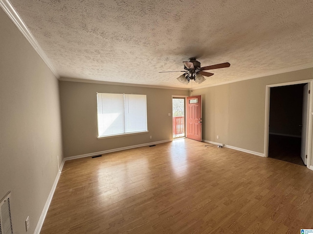 unfurnished room with baseboards, wood finished floors, visible vents, and crown molding