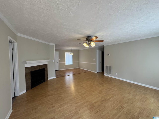 unfurnished living room with crown molding, visible vents, a fireplace, and wood finished floors