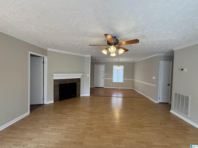 unfurnished living room with ceiling fan, a fireplace, visible vents, baseboards, and light wood-type flooring