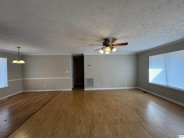 spare room with baseboards, visible vents, wood finished floors, crown molding, and ceiling fan with notable chandelier