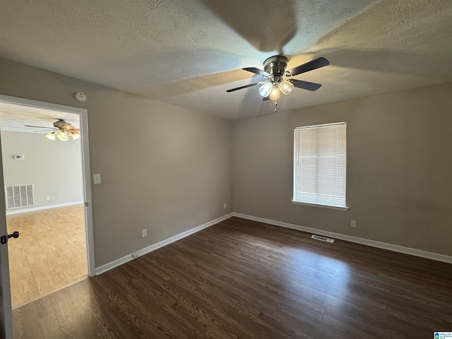 empty room featuring baseboards, visible vents, and wood finished floors