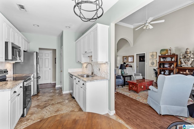 kitchen featuring arched walkways, stainless steel appliances, visible vents, white cabinetry, and a sink