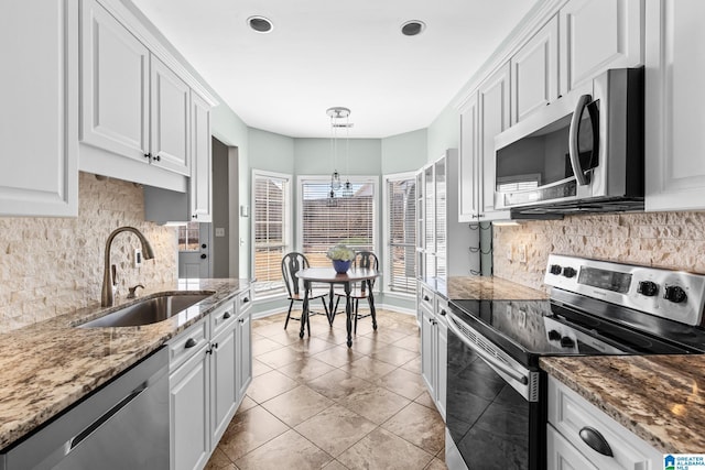 kitchen with light tile patterned flooring, a sink, white cabinetry, appliances with stainless steel finishes, and light stone countertops