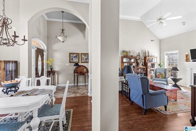 interior space with arched walkways, a fireplace, ornamental molding, wood finished floors, and high vaulted ceiling