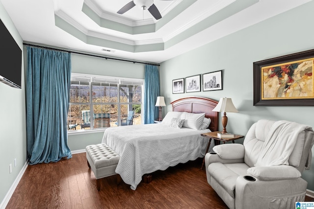 bedroom featuring baseboards, visible vents, wood-type flooring, a tray ceiling, and crown molding