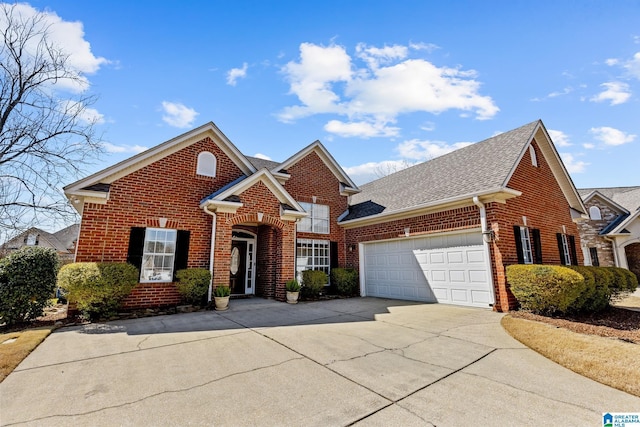 traditional-style house with a garage, driveway, brick siding, and roof with shingles