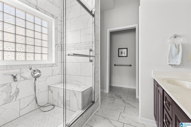 full bath featuring marble finish floor, a marble finish shower, baseboards, and vanity