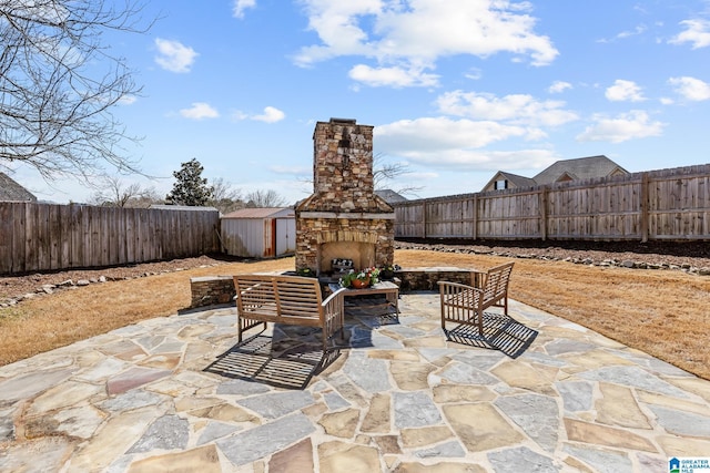 view of patio featuring a storage shed, an outdoor fireplace, and a fenced backyard