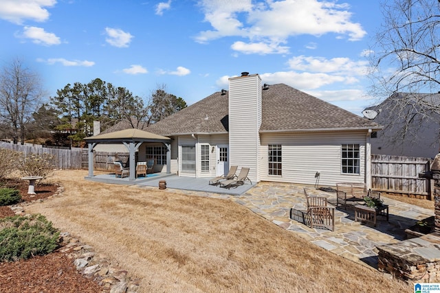 rear view of property featuring a patio, a chimney, a gazebo, and fence