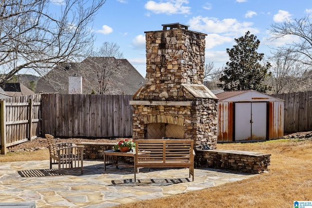 view of patio / terrace with a fenced backyard, an outdoor structure, a storage shed, and an outdoor living space with a fireplace