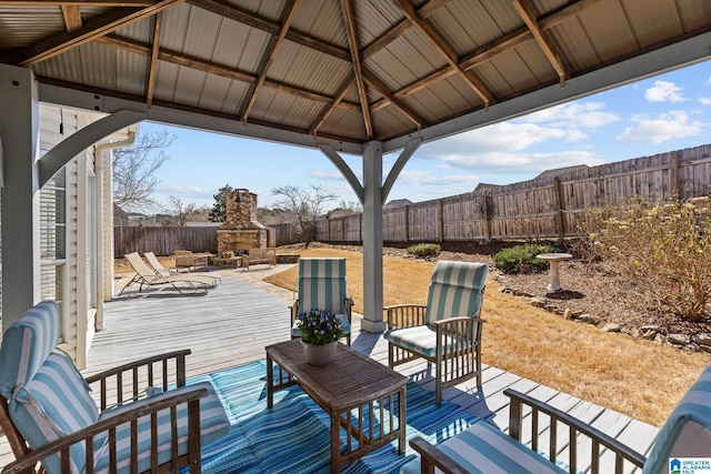 wooden deck featuring a patio area, a fenced backyard, a gazebo, and an outdoor living space with a fireplace