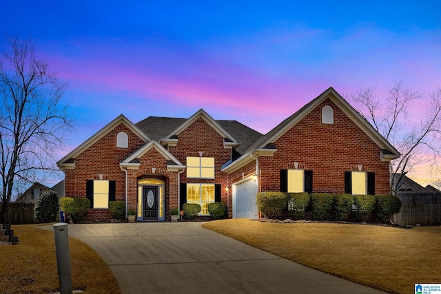 traditional-style house featuring a garage, concrete driveway, brick siding, and a yard