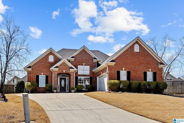 traditional-style house with a garage, driveway, fence, a front lawn, and brick siding