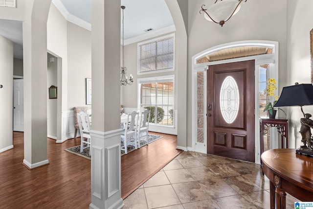 entrance foyer featuring a notable chandelier, a high ceiling, wood finished floors, baseboards, and crown molding