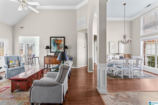 living area with high vaulted ceiling, visible vents, crown molding, and wood finished floors