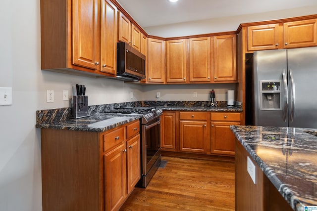 kitchen with stainless steel appliances, dark wood-style flooring, and brown cabinets