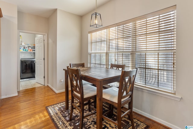 dining area featuring light wood-type flooring, washer / clothes dryer, and baseboards