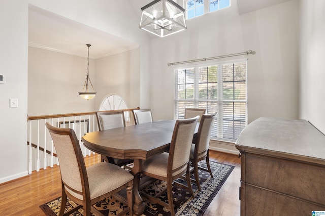 dining space with a notable chandelier, crown molding, baseboards, and wood finished floors