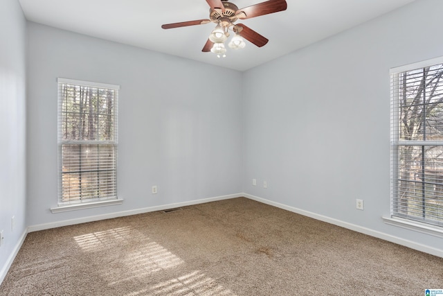 carpeted spare room with ceiling fan and baseboards