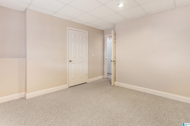 spare room with carpet floors, a drop ceiling, and baseboards