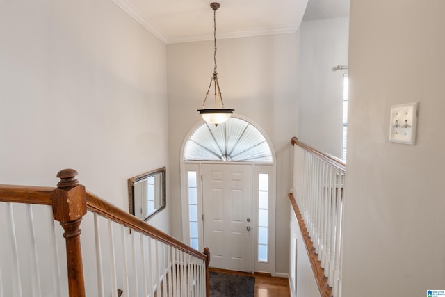 entryway with a high ceiling, ornamental molding, and wood finished floors