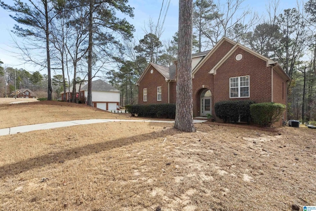 view of front of property with a garage, brick siding, and an outdoor structure