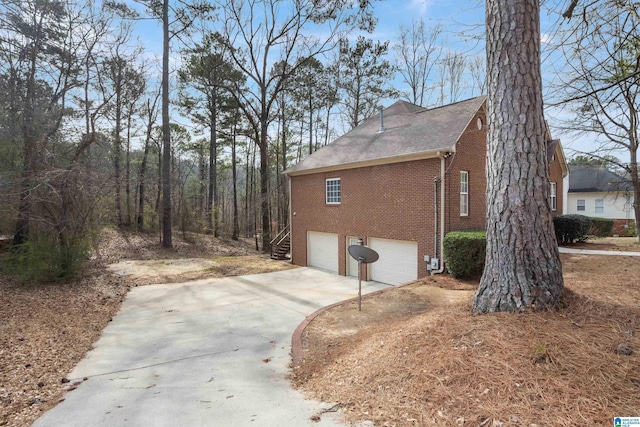 view of side of home featuring a garage, concrete driveway, and brick siding