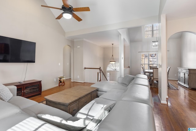 living area featuring baseboards, arched walkways, a ceiling fan, wood finished floors, and high vaulted ceiling