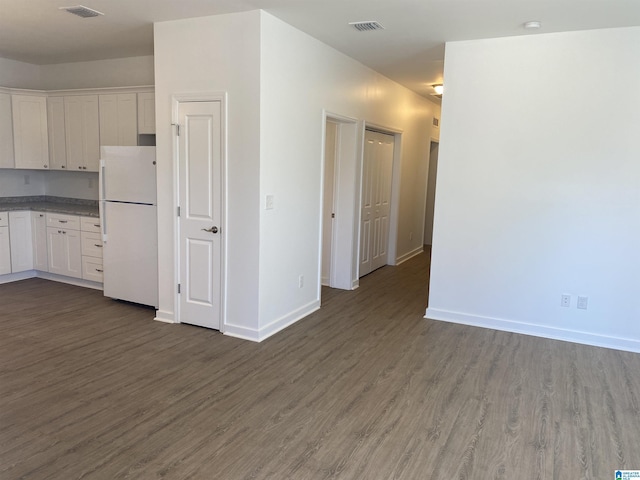 kitchen with wood finished floors, visible vents, baseboards, white cabinets, and freestanding refrigerator