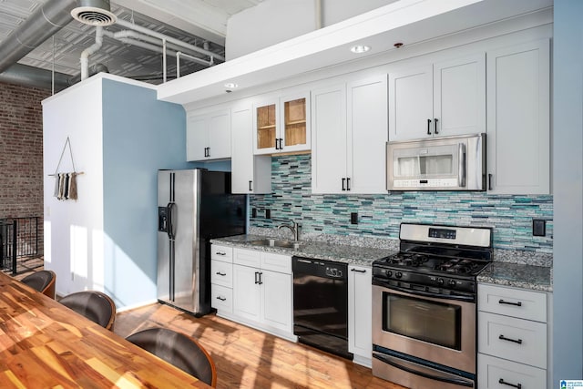 kitchen featuring appliances with stainless steel finishes, backsplash, a sink, and light stone counters