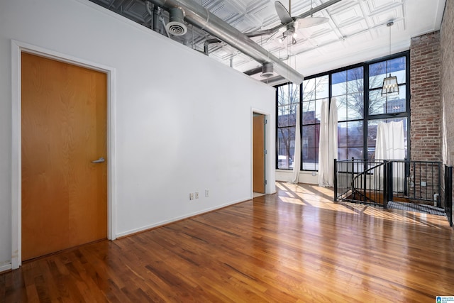 unfurnished room with an ornate ceiling, ceiling fan, a high ceiling, and wood finished floors