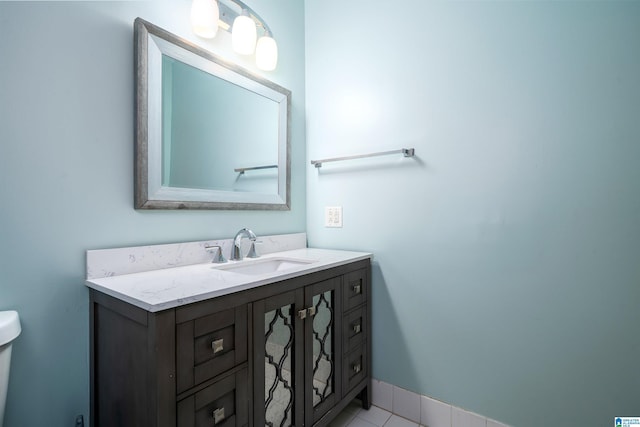 bathroom featuring tile patterned flooring, baseboards, vanity, and toilet