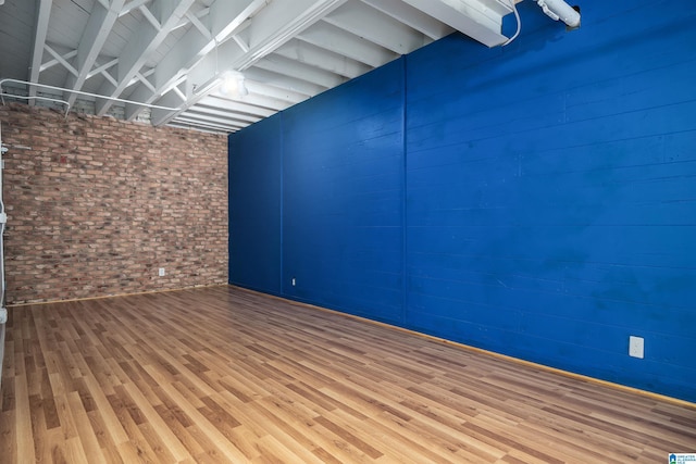 empty room featuring brick wall and wood finished floors