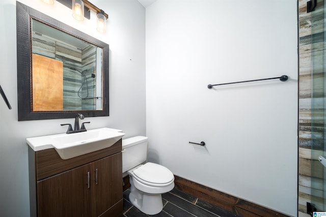 bathroom with wood finished floors, vanity, toilet, and baseboards