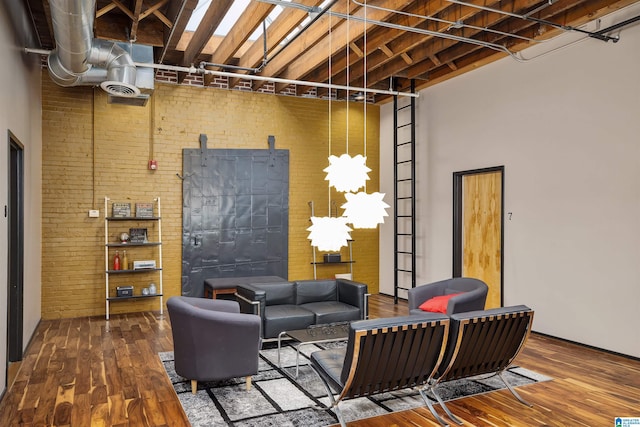 living room featuring visible vents, a towering ceiling, brick wall, and wood finished floors