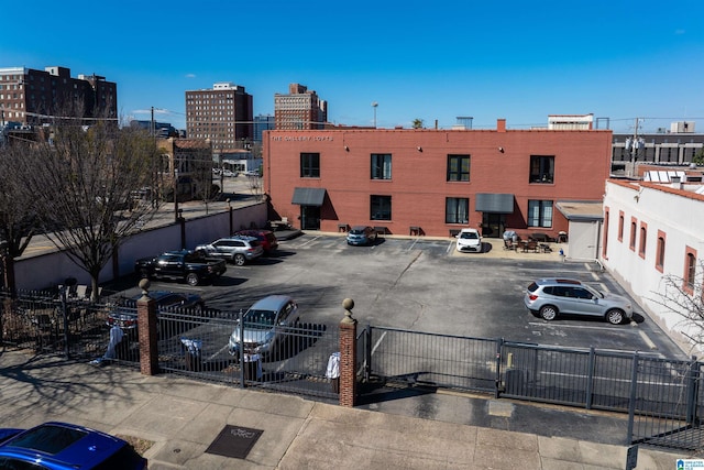 uncovered parking lot featuring a view of city, fence, and a gate