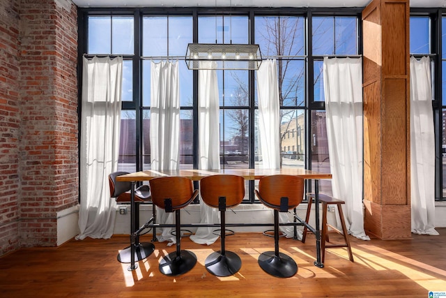 bar with expansive windows, brick wall, and wood finished floors