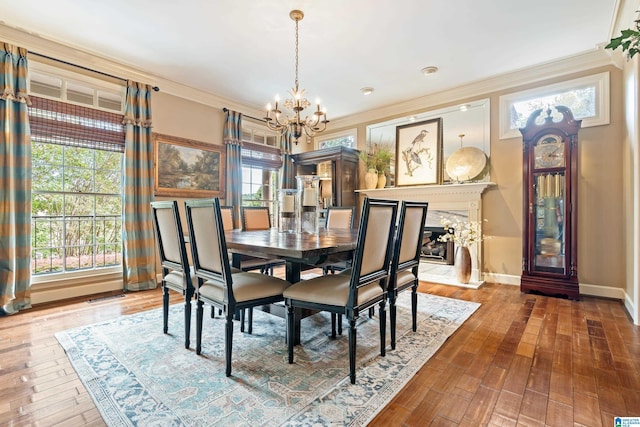 dining space with baseboards, visible vents, wood finished floors, crown molding, and a chandelier