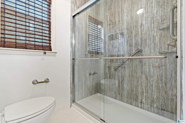 bathroom with a stall shower, toilet, and baseboards