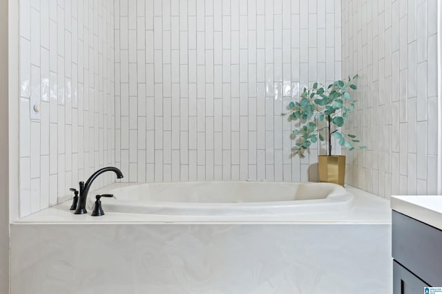 bathroom with a garden tub, tile walls, and vanity