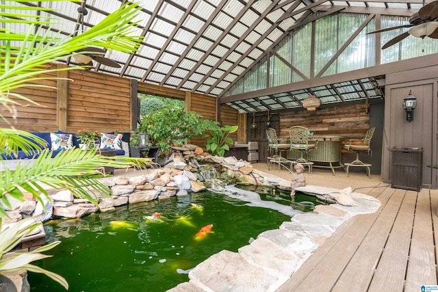 unfurnished sunroom with vaulted ceiling and a small pond