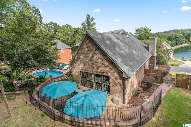 rear view of house featuring brick siding, fence, a yard, a fenced in pool, and a gate