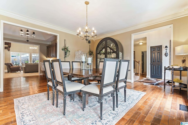 dining space with ornamental molding, wood finished floors, baseboards, and an inviting chandelier