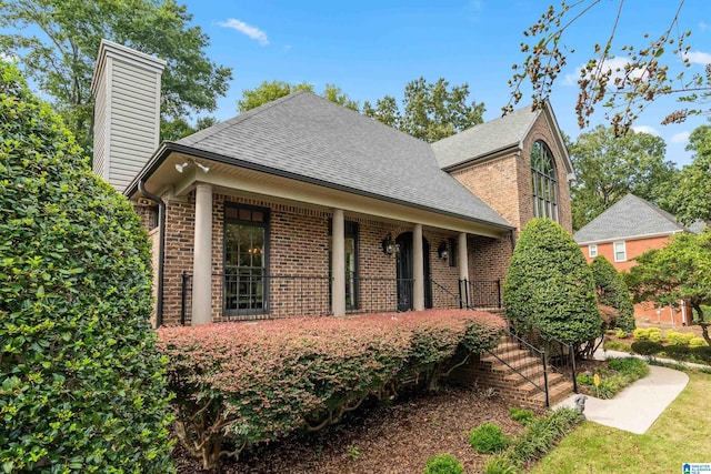 traditional-style house with brick siding, stairway, and a shingled roof