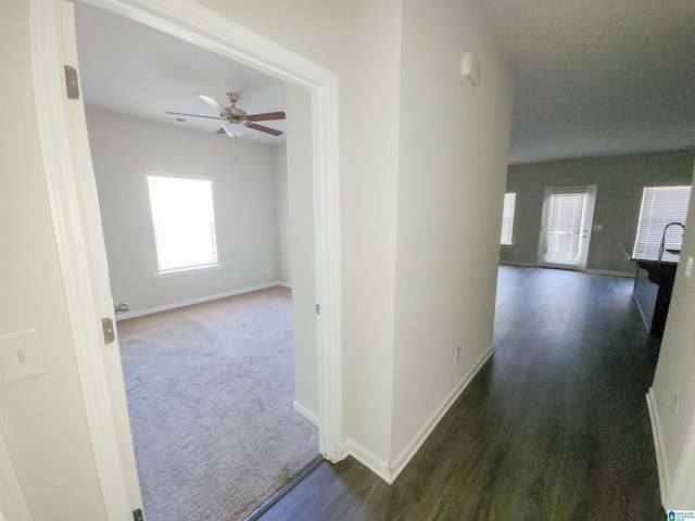 hall with carpet flooring, baseboards, and wood finished floors