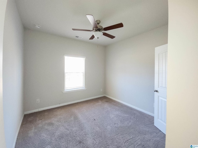 carpeted spare room with baseboards, visible vents, and ceiling fan