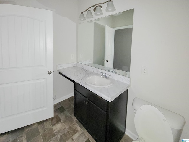 bathroom featuring toilet, baseboards, and vanity